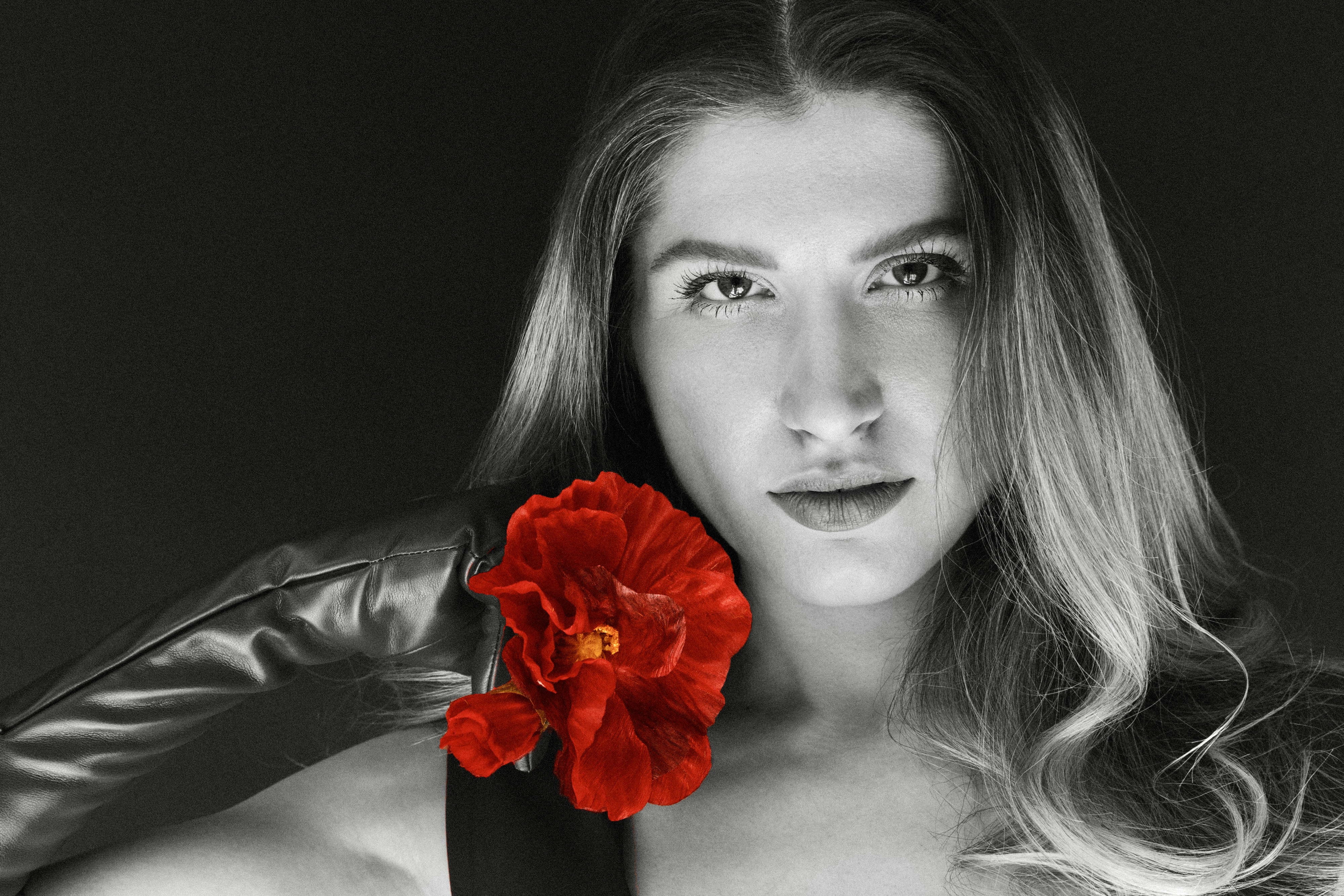 Ilana Kovalle in a black-and-white portrait with a red flower